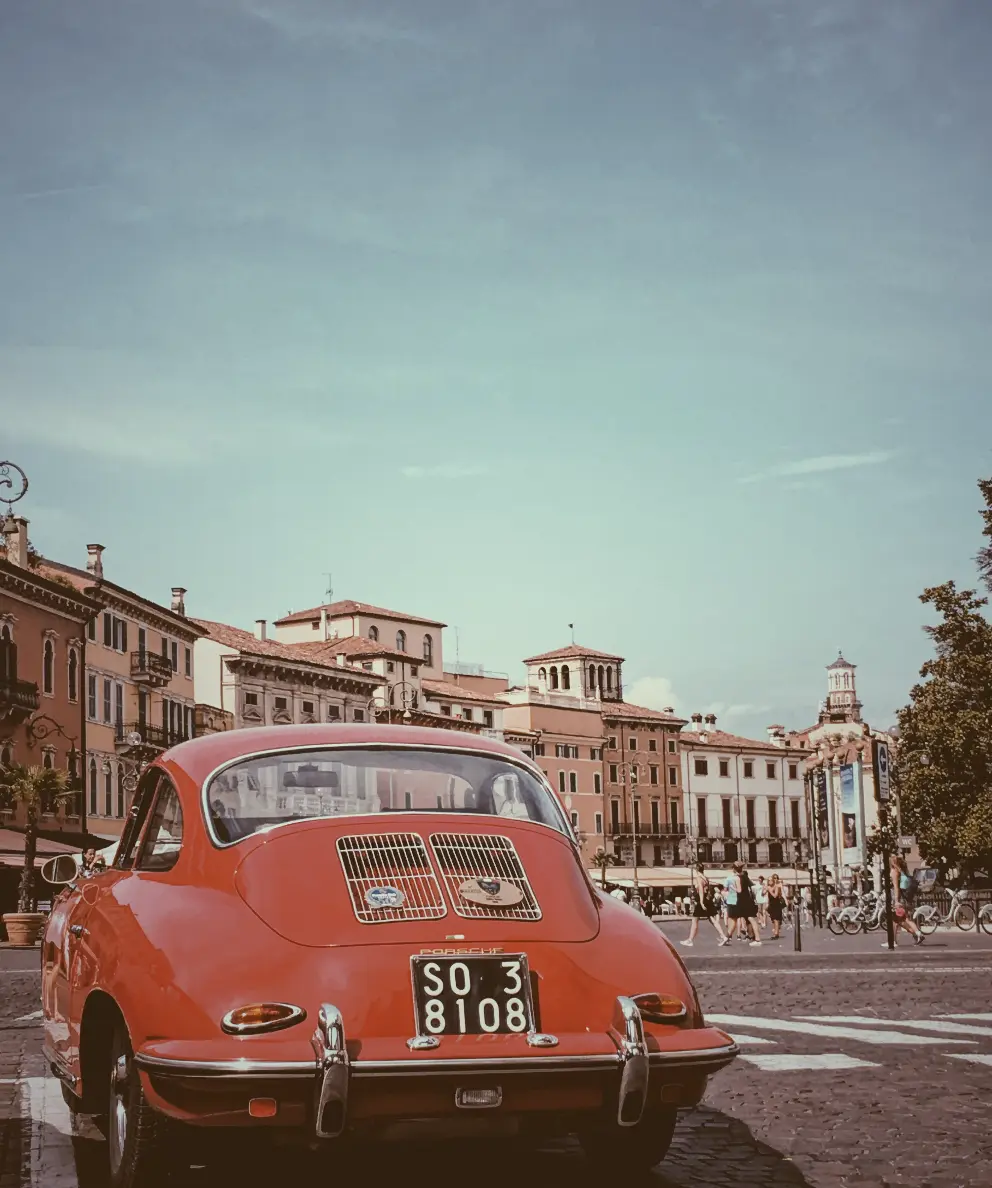 Image without css filter: grayscale(%). This image shows a photo of a red car with old buildings as a background.This photo was captured in Verona city Italy.