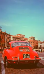 Vibrant red car against old buildings in Verona city, Italy, with CSS saturate filter set to 200%.