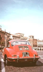 A photo of a red car with old buildings in the background, captured in Verona, Italy. The image has a CSS filter with 150% brightness, making it brighter than the original.