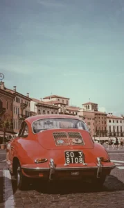 A photo of a red car with old buildings as a background.This photo was captured in Verona city Italy.