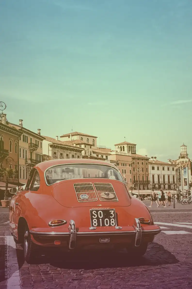 Utilizing the linear-gradient overlay. This image shows a photo of a red car with old buildings as a background.This photo was captured in Verona city Italy. We set the background-image: linear-gradient(
rgba(0, 255, 255, 0.3),
rgba(255, 255, 0, 0.2),
rgba(155, 0, 155, 0.2)
); and it adds a line drawing overlay from top to bottom with shades of teal, yellow, and purple.